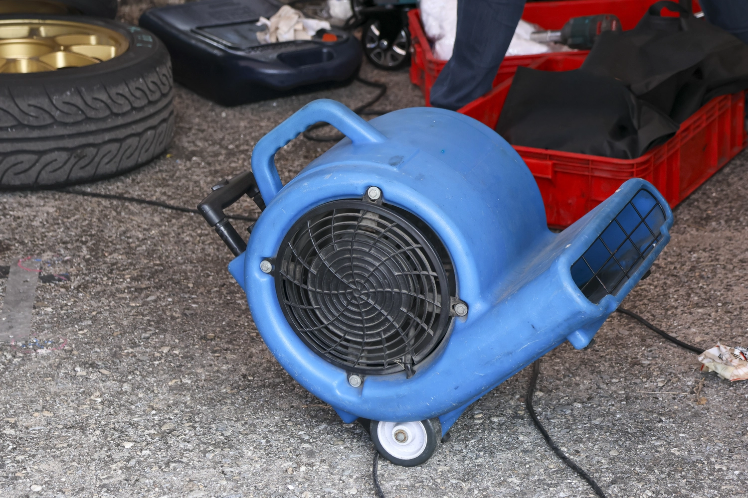 R.S Sicco UG – Wasser- & Brandschadensanierung, Reinigung und Gebäudedienste - Ein leistungsstarker blauer Industrielüfter steht auf dem Betonboden in der Garage.