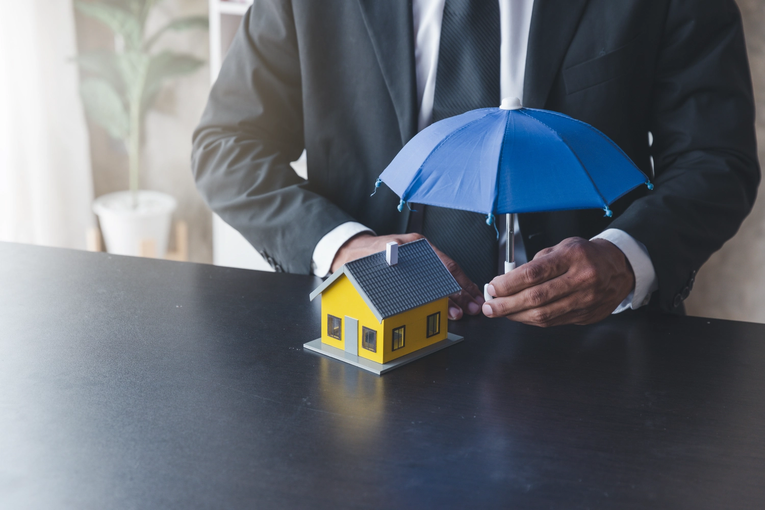 R.S Sicco UG – Wasser- & Brandschadensanierung, Reinigung und Gebäudedienste - Konzept der Hausratversicherung: Versicherungsagent nutzt einen Schutzschirm, um das Haus abzusichern.